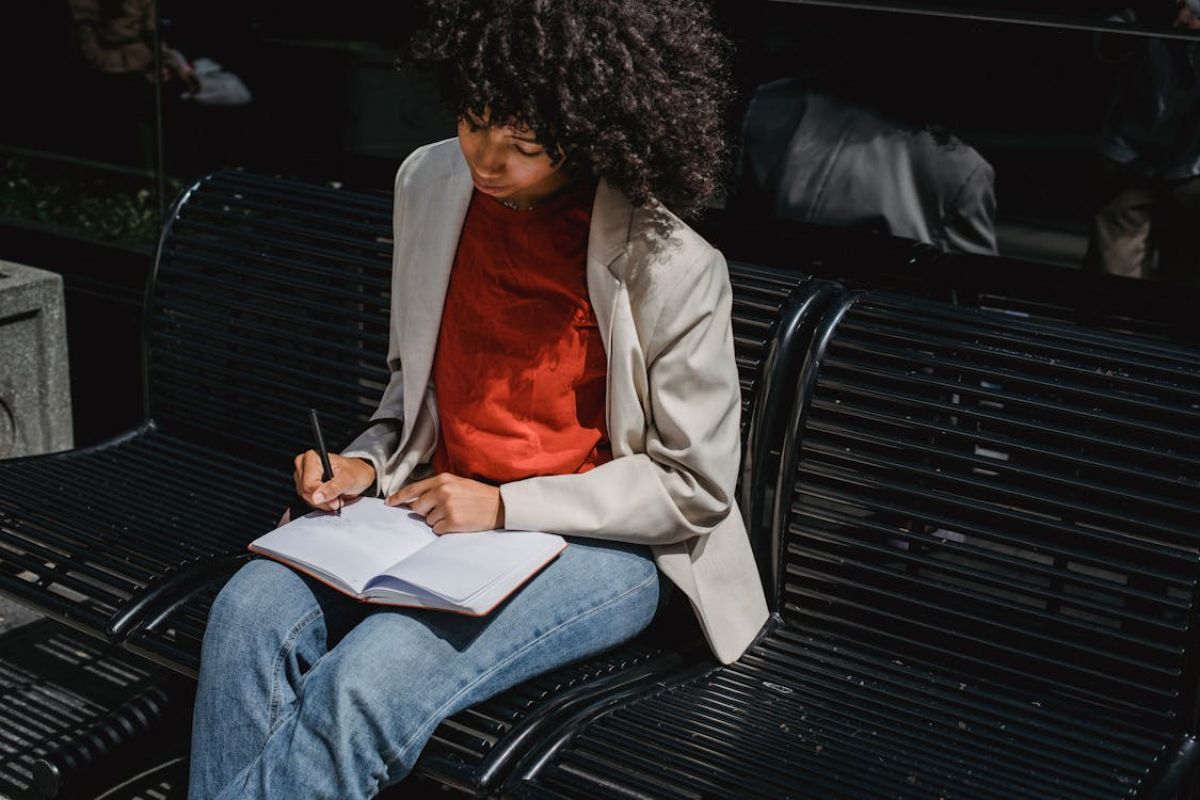 Uma mulher em casa estudando. Ela faz anotações em um caderno sobre a Inscrição Concurso Banco Brasil 2025