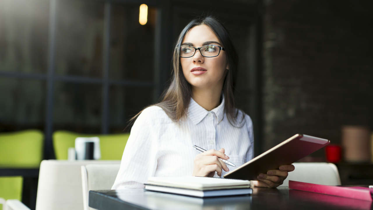 Mulher jovem estudando em cafeteria para inscrição da OAB 2025