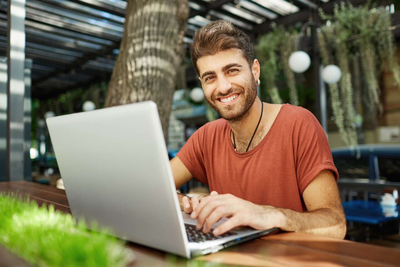 Jovem trabalhando no notebook posa sorridente 