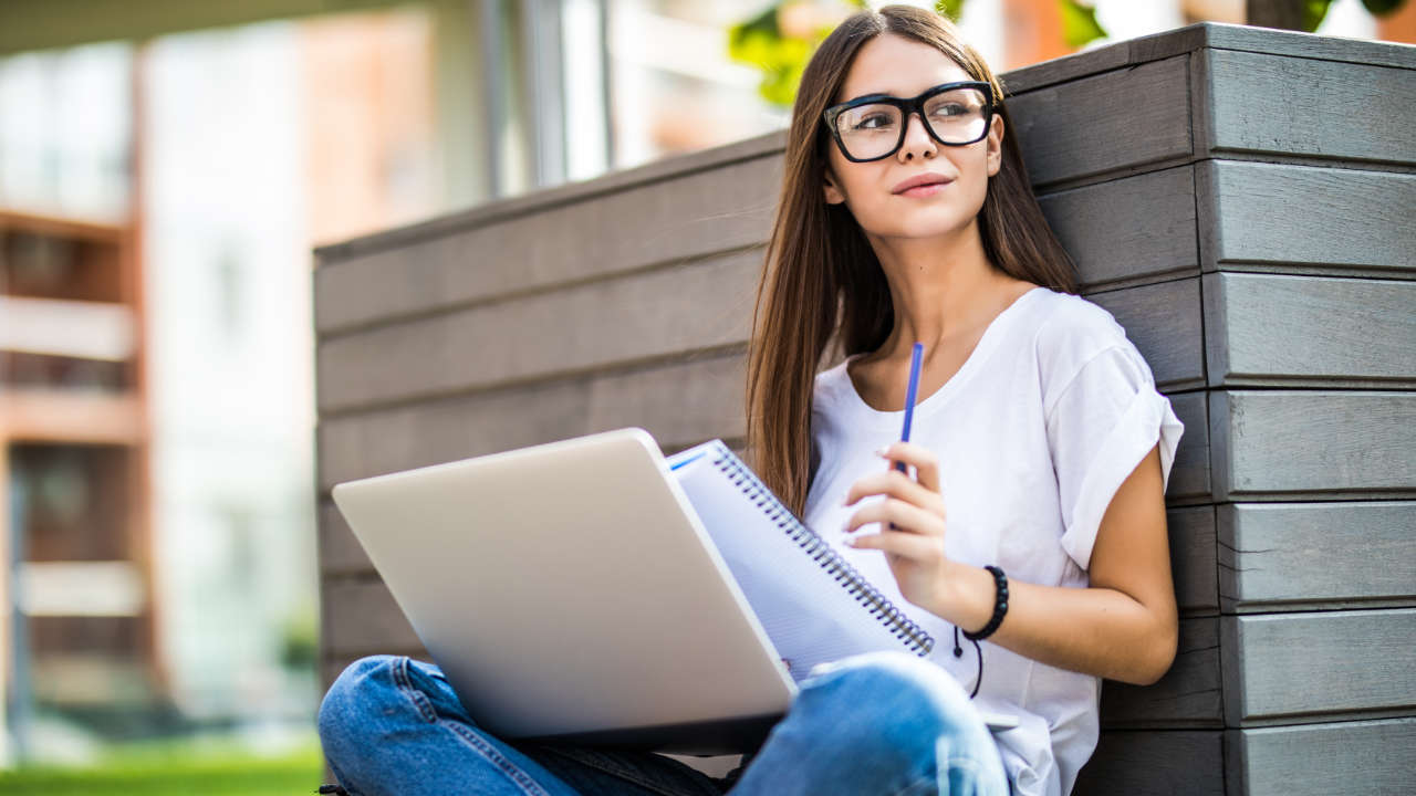 Mulher jovem usando laptop sentado no banco para fazer inscrição UFPA 2025