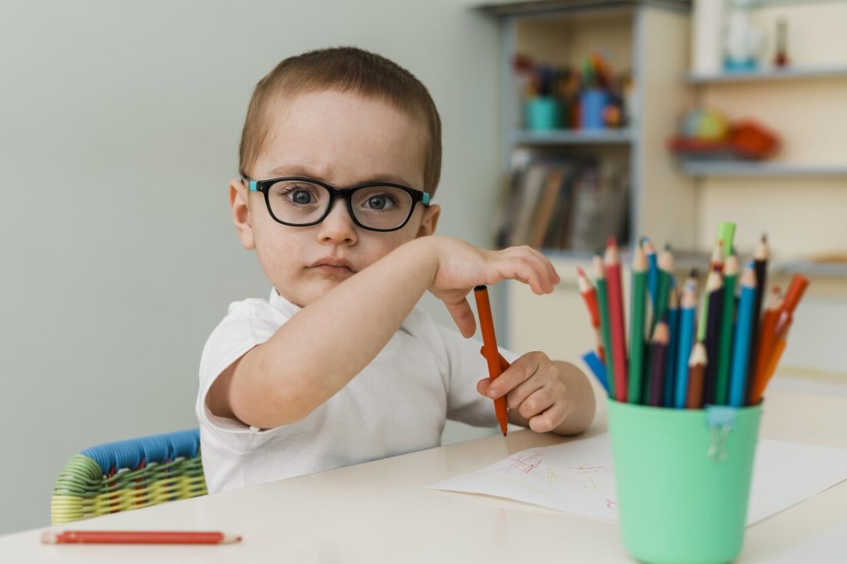 Criança pintando em sua mesa na escola de Educação Infantil 