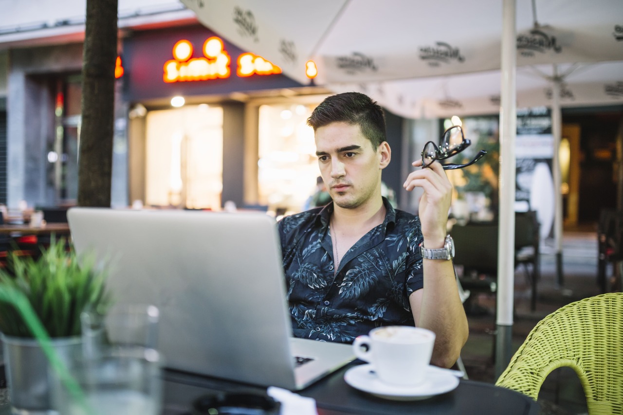 Jovem trabalha em seu computador em uma cafeteria