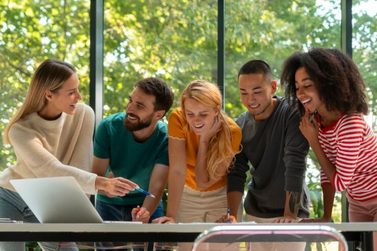 Um grupo de estudantes na sala de aula conversam enquanto alguns se apoiam na mesa e outros explicam como funciona a Inscrição UFPR 2025 Doutorado