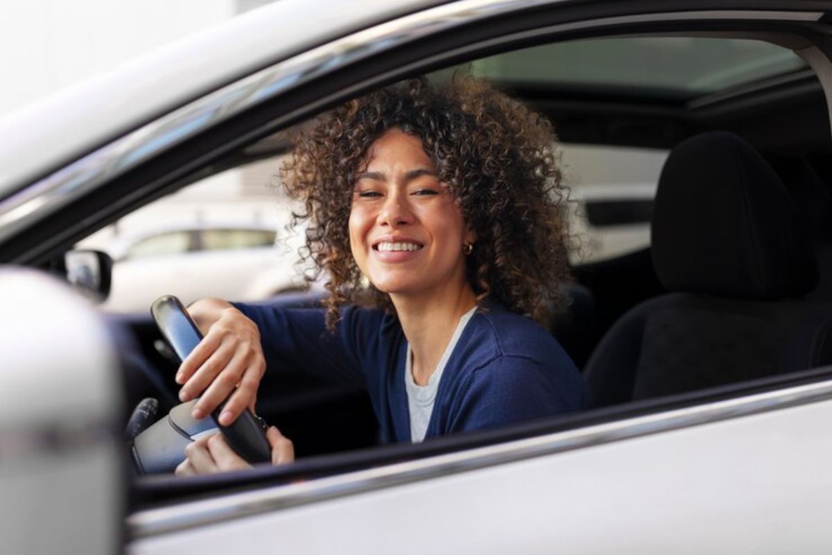 Uma motorista sorrindo dentro do seu carro após fazer a Inscrição Uber 2025