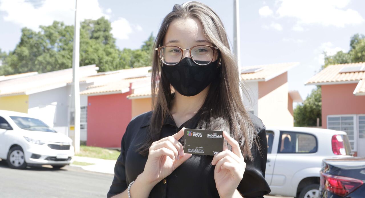 Jovem mostra cartão do programa Bolsa do Povo 