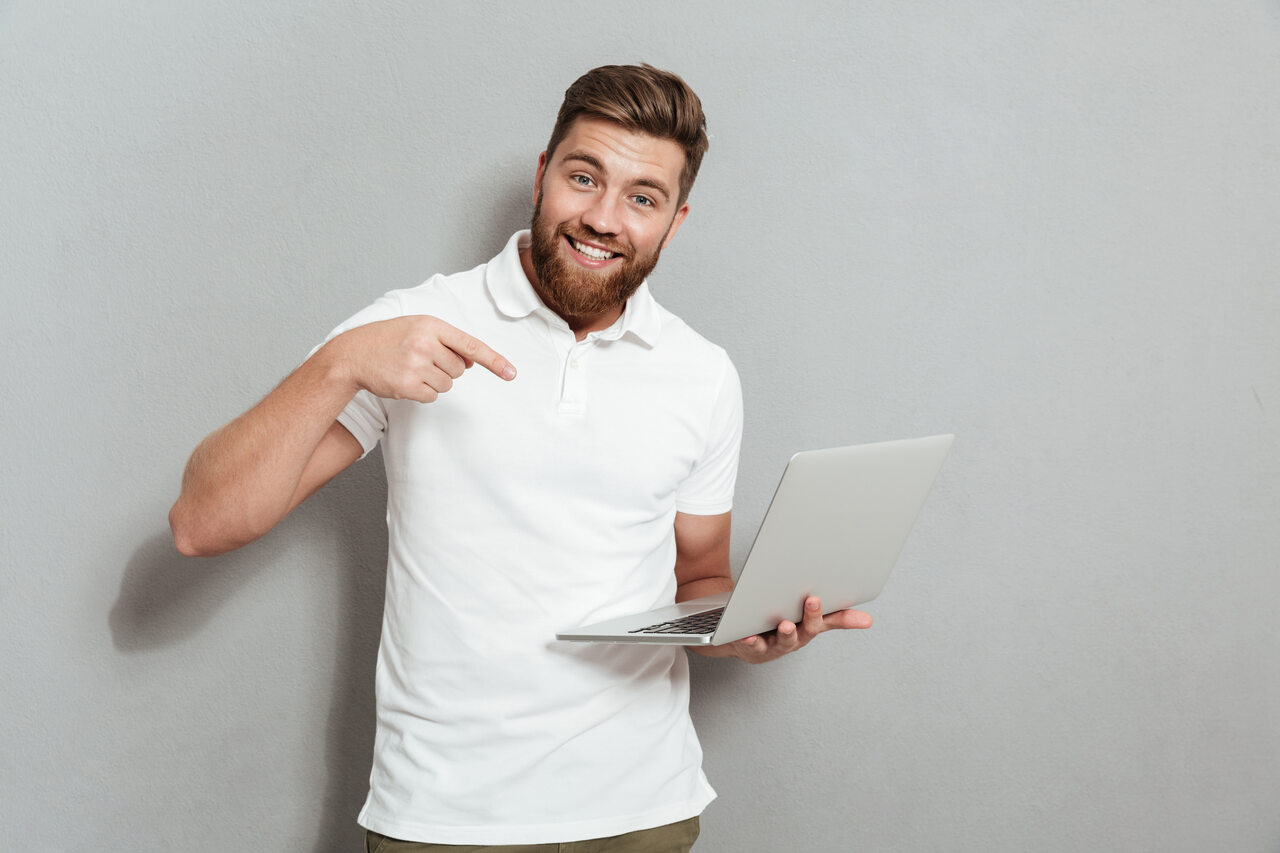 Jovem aponta para notebook em sua mão 