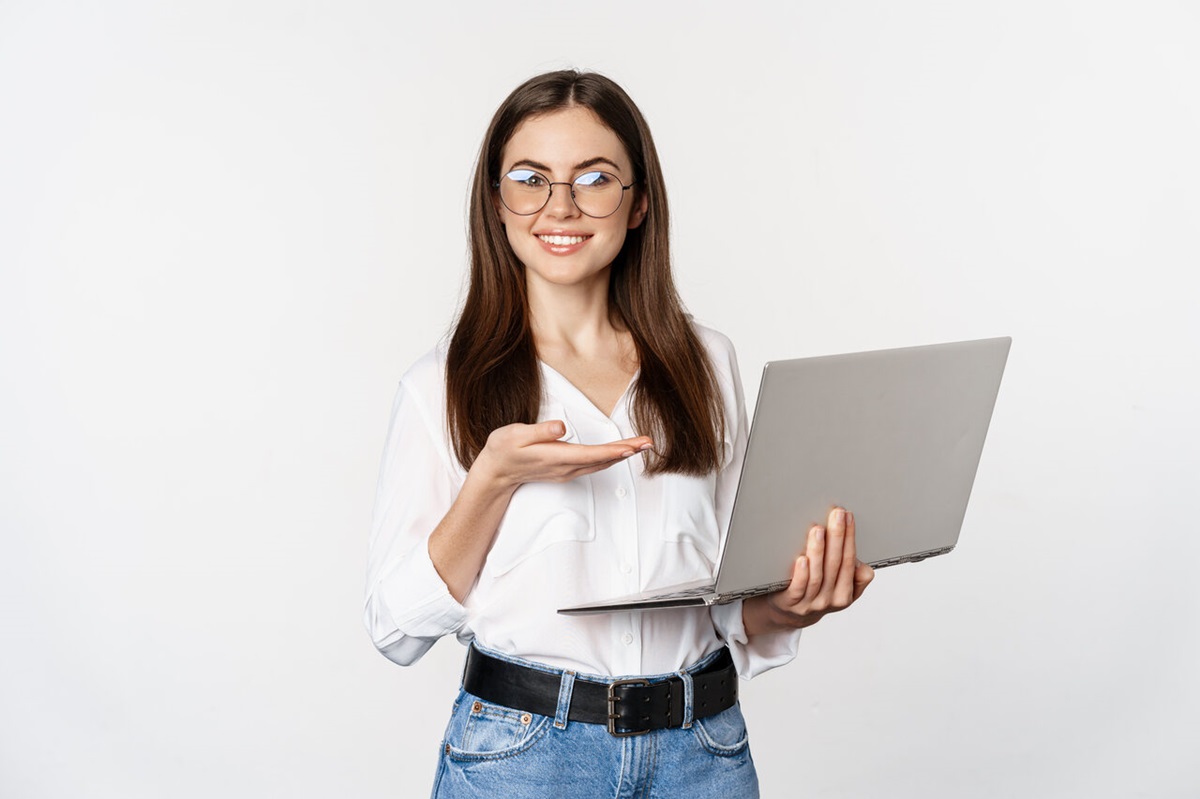 Mulher de pé aponta para notebook aberto em sua mão