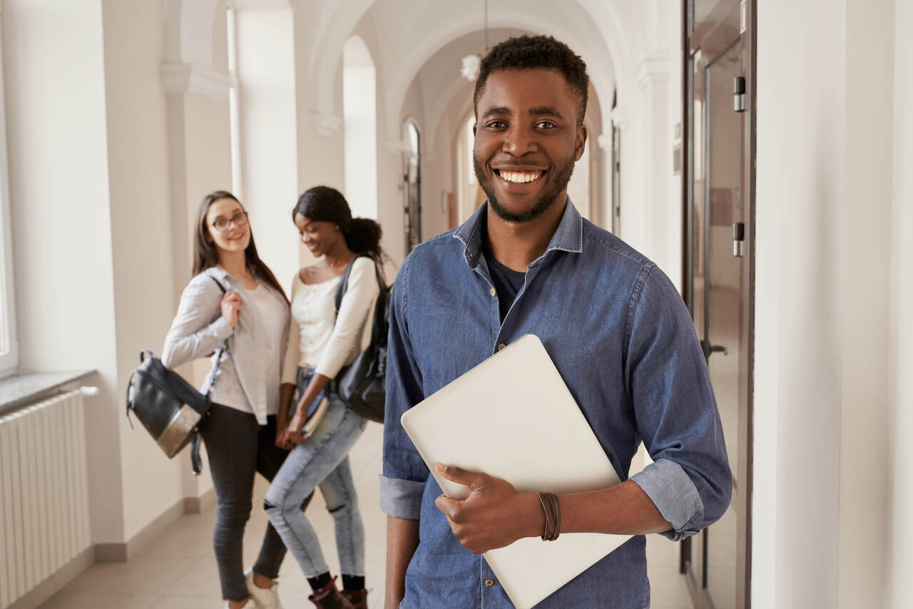 Jovem estudante no corredor da universidade com colegas ao fundo 