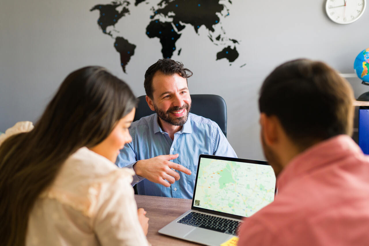 Profissional de turismo indica em mapa de seu notebook ponto turístico para visitantes 